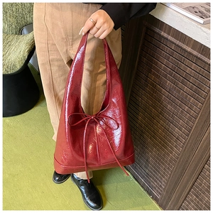 Detailed view of the dark red patent leather hobo tote bag featuring a decorative bow tie
