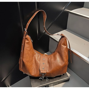 Detail of a brown pleated leather tote bag with star rivets and adjustable shoulder strap
