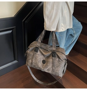Dettaglio di una grande borsa da viaggio con texture opaca vintage su scale in legno