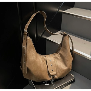 Detail of brown hobo shoulder bag featuring silver star rivets and soft leather texture