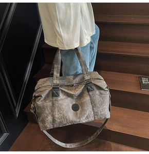 Dettaglio del grande borsone da viaggio con trama in tela grigia e patch logo in pelle