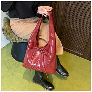 Detail of burgundy glossy leather tote bag with elegant bow decoration in a retro setting