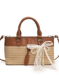 Fashionable straw tote bag with brown leather trim, lace bow, and pearl charm detail