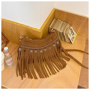Détail du sac bohème en daim marron avec de longues franges et des breloques en pièces