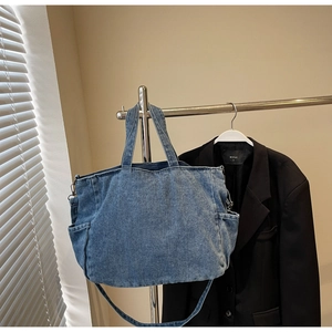 Detail of blue denim tote bag side pocket and washed texture hanging on rack