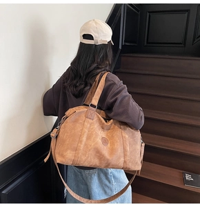 Borsa da viaggio in pelle marrone con tracolla presentata in una scena di stile di vita