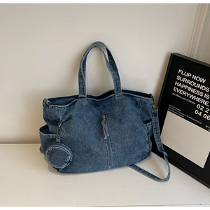 Detail of blue denim tote bag showing side pockets and decorative round coin purse