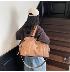 Borsa da viaggio vintage marrone in pelle con tracolla sulle scale interne