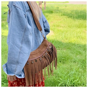 Détail du sac bohème en daim marron avec franges, broderies et disques métalliques