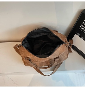 Dettaglio interno della borsa da viaggio marrone con fodera in tessuto nero e tasca a zip