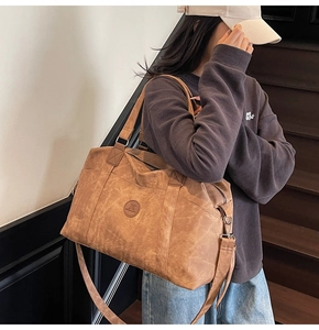Vista dettagliata della borsa da viaggio in pelle marrone vintage con tracolla e logo