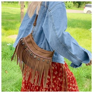 Détail d'un sac à bandoulière en daim marron bohème avec pompons et ornements ethniques