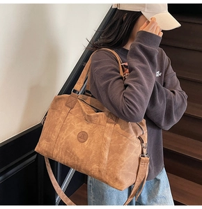 Dettaglio di una grande borsa da viaggio marrone con trama opaca e tracolla regolabile