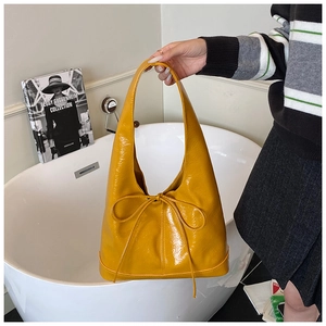 Close-up of the glossy yellow hobo bag featuring a stylish bow and pleated leather texture
