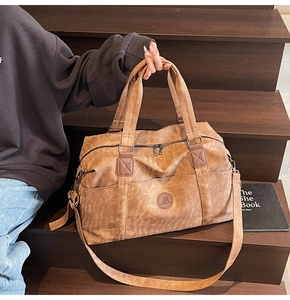 Vista dettagliata di una grande borsa da viaggio in ecopelle marrone su scale in legno