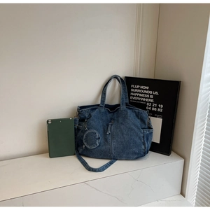 Close-up of denim tote bag showing vertical zipper detail and small round coin purse