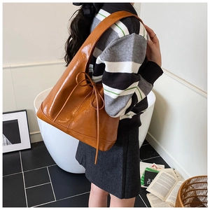 Detail of caramel brown glossy tote bag with stylish side bow tie and smooth leather texture