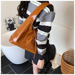 Detailed side view of caramel brown faux leather tote bag with stylish bow drawstring decoration