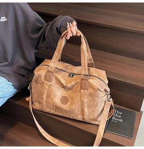 Dettaglio borsa da viaggio vintage in tela marrone con logo e cerniere resistenti