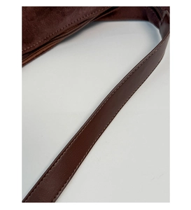 Detailed close-up of dark brown suede tote with leather strap and refined stitching