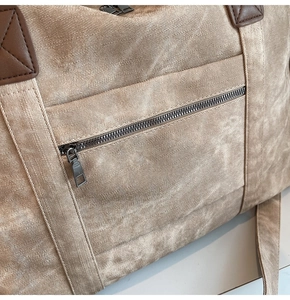 Dettaglio della borsa da viaggio in tela con cerniere metalliche e inserti in pelle