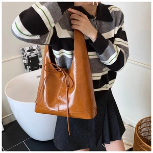 Detail of caramel tote bag with patent leather texture and stylish bow tie decoration