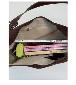 Spacious interior of dark brown suede tote bag showing books and folding umbrella