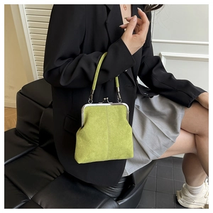 Detail of avocado green vintage kiss-lock handbag with matte finish held by a model
