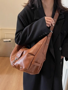 Retro brown leather tote bag with star studs and adjustable strap on a black coat