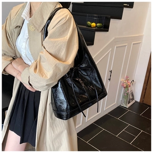 Detail of black glossy oiled leather tote bag with drawstring side ties for commuting