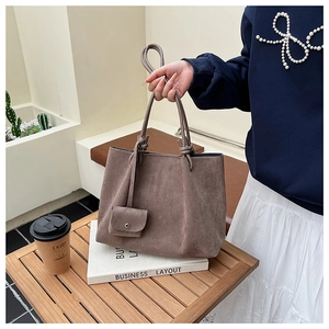 Detail of vintage matte brown tote bag with small coin purse on a wooden table
