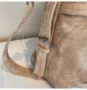 Dettaglio della borsa da viaggio beige in tela con trama diagonale e fibbie metalliche