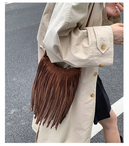 Detail of a brown suede crossbody bag with long fringes and bohemian street style aesthetic
