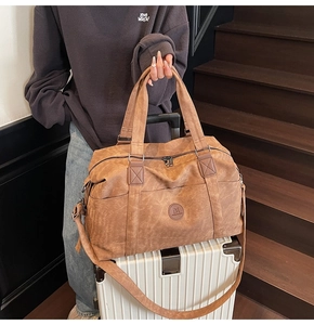 Borsa da viaggio vintage in pelle PU marrone capiente posizionata su una valigia bianca