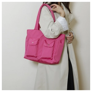 Detail of rose pink nylon tote bag with functional front flap pockets and side pocket