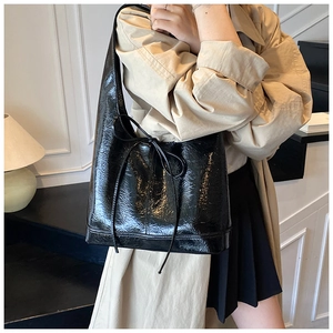 Detail of black glossy crinkled leather texture and delicate bow on a tote bag