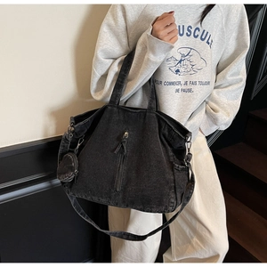 Detail view of large washed denim tote bag with vertical zipper and mini coin purse