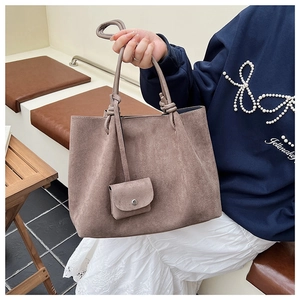 Detail of tan matte leather tote bag featuring a unique knotted handle and matching pouch