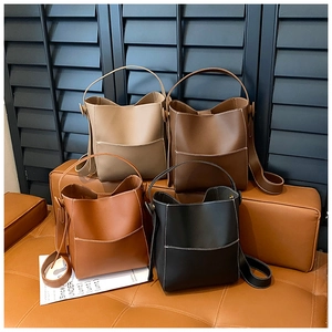 Detail view of four minimalist bucket bags in beige, brown, tan, and black leather