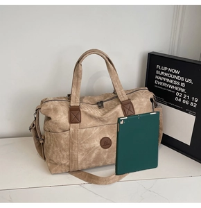 Dettaglio della grande borsa da viaggio in tela con manici in pelle PU e tracolla regolabile