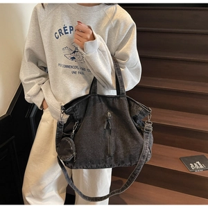 Detailed view of black denim moto tote bag with tassel zippers and small round coin purse