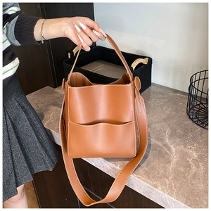 Détail du sac seau en cuir marron montrant la poche ondulée et surpiqûres blanches
