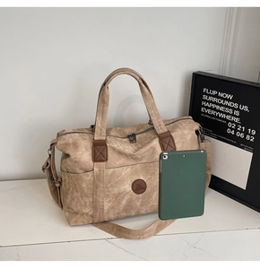 Grande borsa da viaggio in tela kaki con manici in pelle accanto a un tablet verde