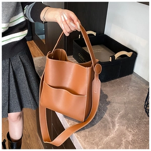 Détail d'un sac seau marron avec surpiqûres blanches et poche à bordure ondulée élégante