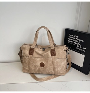 Dettaglio borsa da viaggio in tela kaki con logo in pelle su piano di marmo