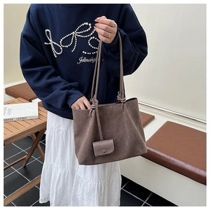 Detail of dark brown faux suede tote bag featuring a mini pouch and knotted handle accents