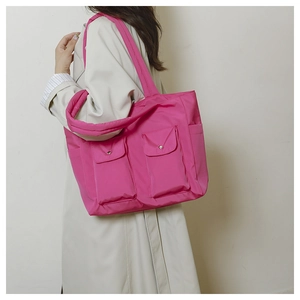 Detail view of pink nylon tote bag with silver snap buttons and dual front pockets