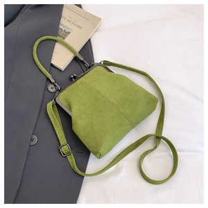 Detail of vintage grass green suede handbag with classic metal frame and thin shoulder strap