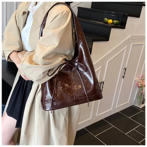 Detail of dark brown glossy Hobo bag featuring a slim drawstring bow on a laptop model