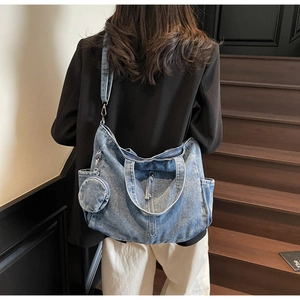 Detail of light blue washed denim tote bag with side pocket and round coin purse attachment